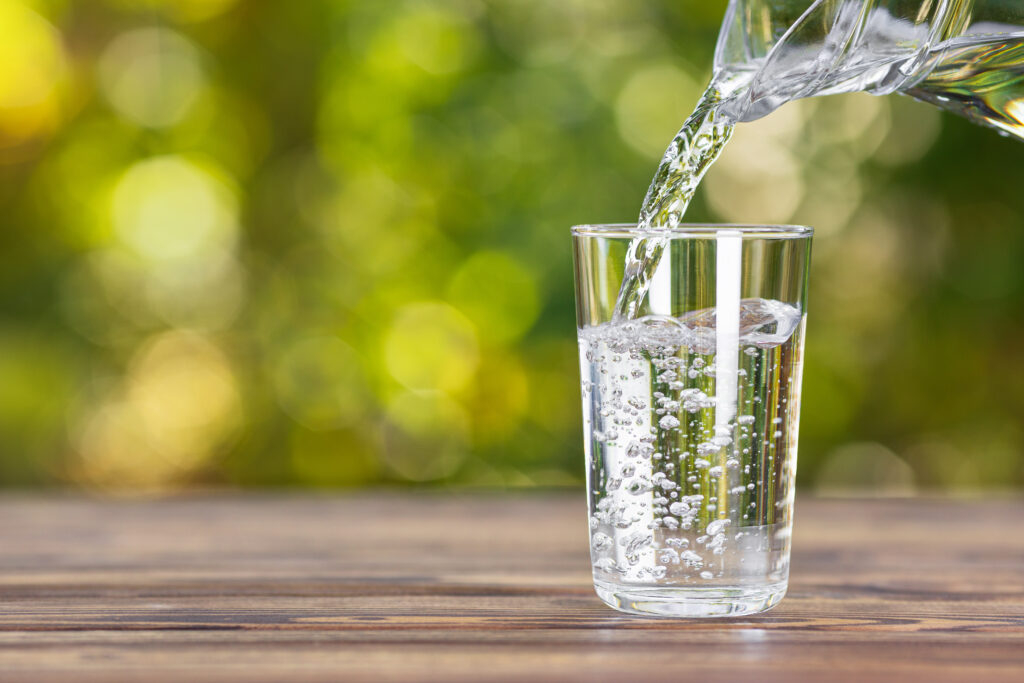 Wasser wird für die Trinkkur in ein Glas geschüttet