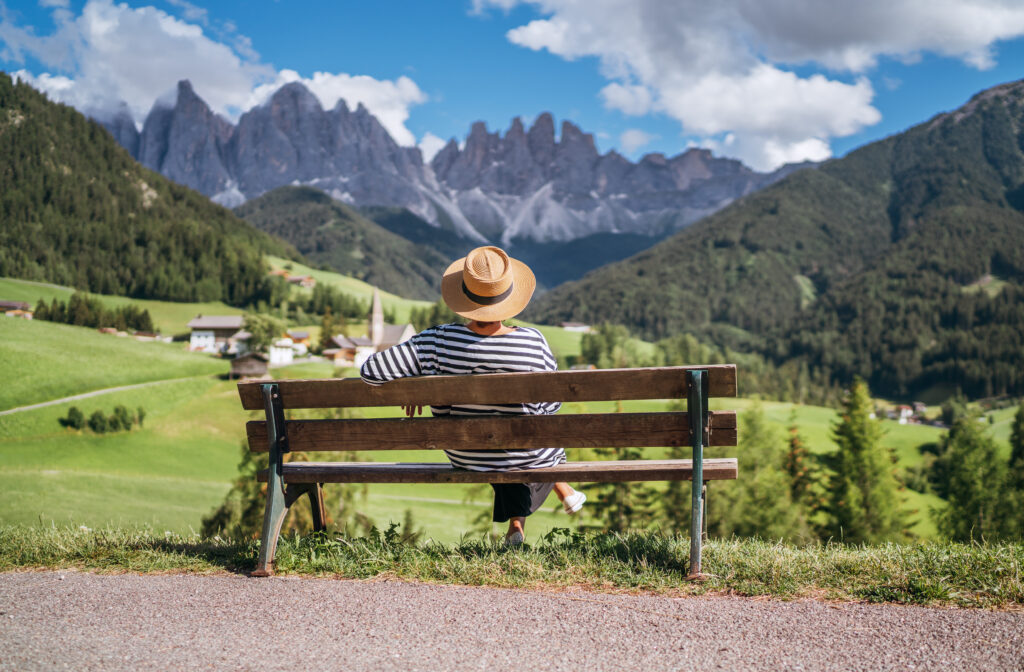 Ein Mann sitzt auf einer Bank mit Blick auf die Alpen