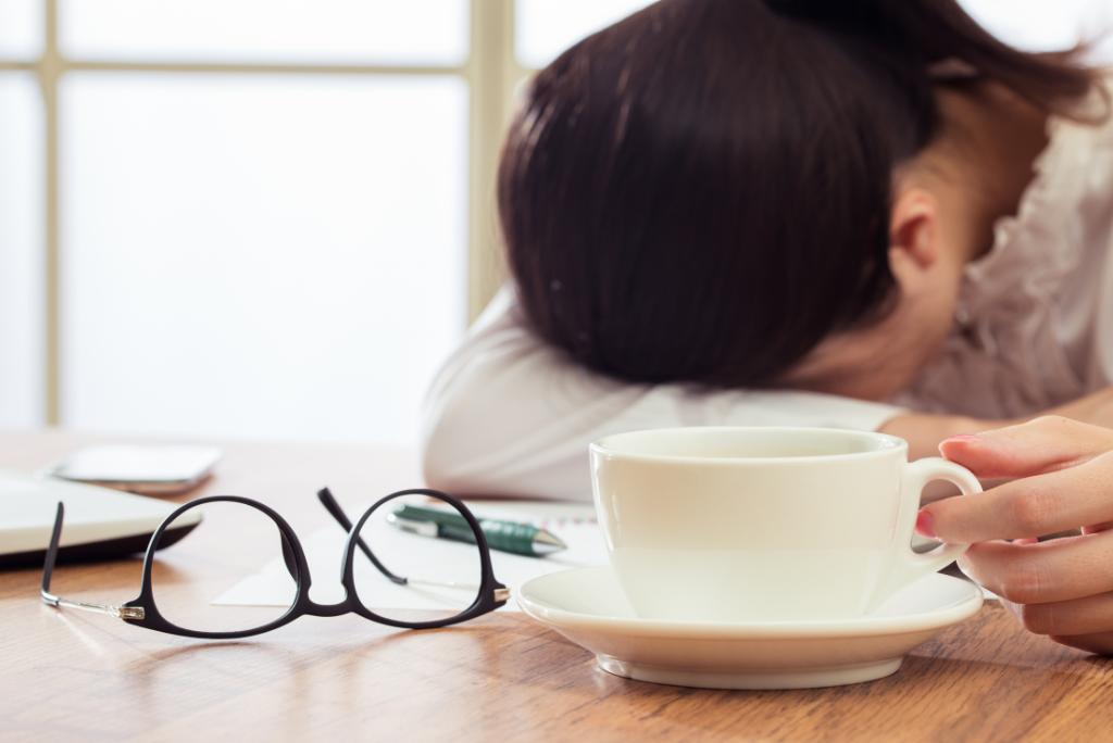 Eine Frau liegt erschöpft mit dem Kopf auf dem Tisch.