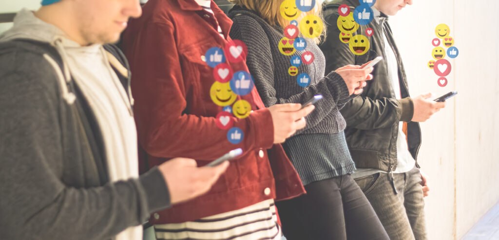 Mehrere Personen schauen auf ihr Smartphone. Emojis, Herzen und Likes sind darüber abgebildet.